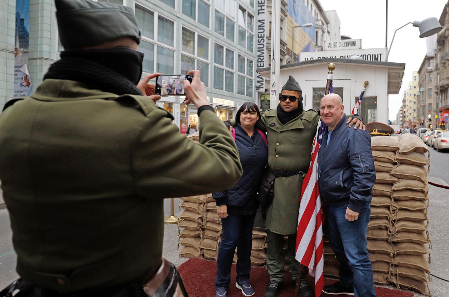 Zwei Touristen aus England lassen sich am Checkpoint Charlie mit einem Mann in US-Uniform fotografieren