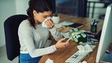 Erkältung: Eine Frau sitzt krank im Büro