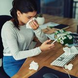 Erkältung: Eine Frau sitzt krank im Büro