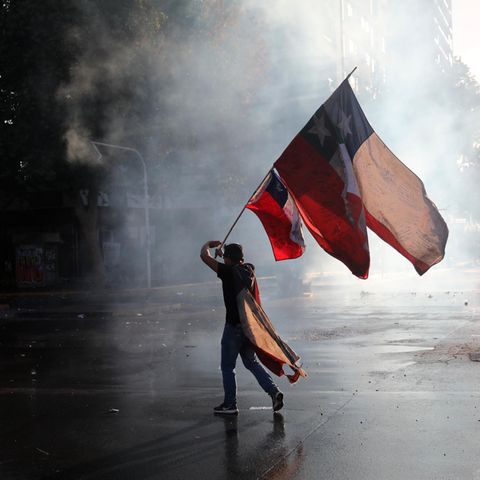 Ein regierungskritischer Demonstrant schwenkt während eines Protests eine chilenische Fahne