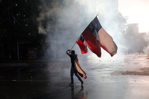 Ein regierungskritischer Demonstrant schwenkt während eines Protests eine chilenische Fahne