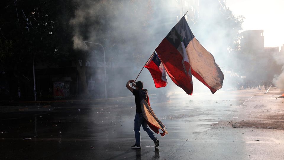Ein regierungskritischer Demonstrant schwenkt während eines Protests eine chilenische Fahne