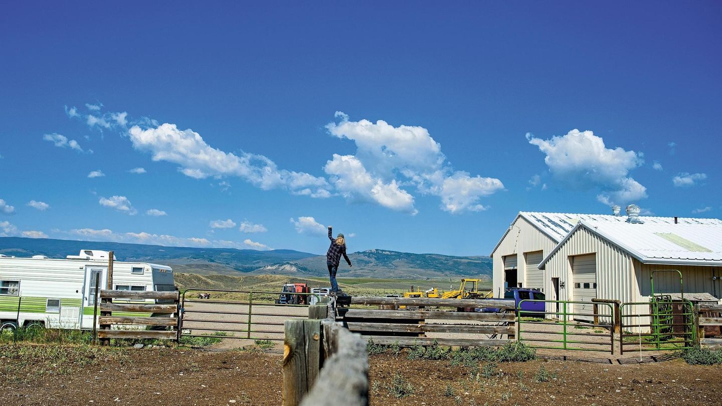 Bild einer Ranch. Auf einem Zaungeländer balanciert Wendy Eller