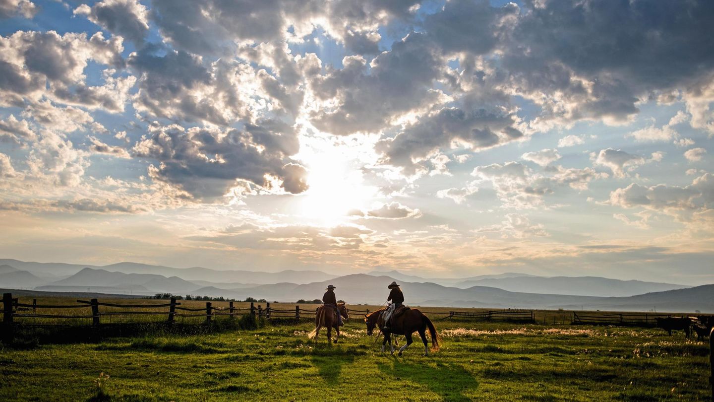 Vicky und Caitlyn auf ihren Pferden vor einer malerischen Kulisse