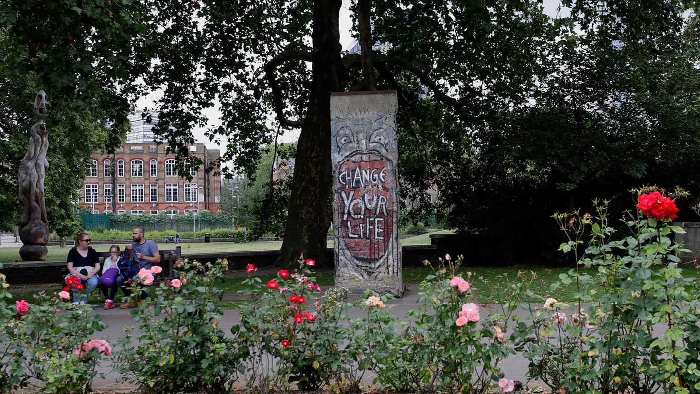 London, Großbritannien: Eine Familie sitzt in der Nähe eines Teils der Berliner Mauer, der aus der Nähe des Brandenburger Tores stammt und 1991 vom Imperial War Museum in London erworben wurde, auf einer Bank.