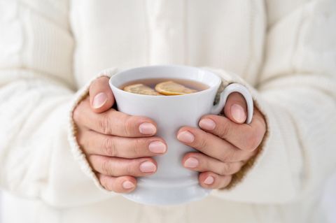 Kalte Hände: Frau hält eine Tasse Tee in der Hand