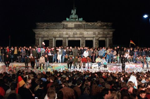 Feiernde Ost- und Westdeutsche auf der Berliner Mauer am Brandenburger Tor in der Nacht des 9. November 1989
