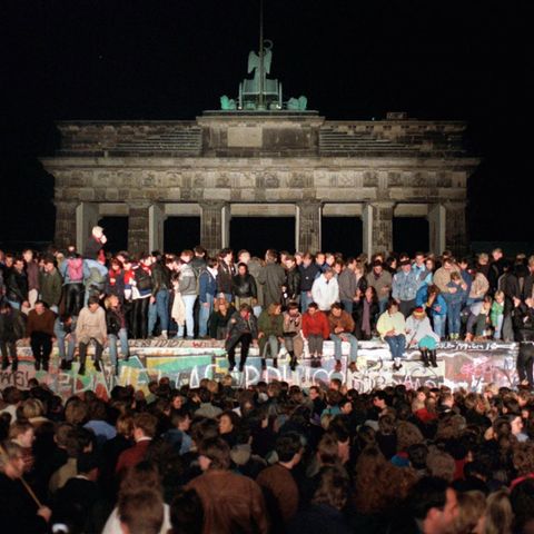 Feiernde Ost- und Westdeutsche auf der Berliner Mauer am Brandenburger Tor in der Nacht des 9. November 1989
