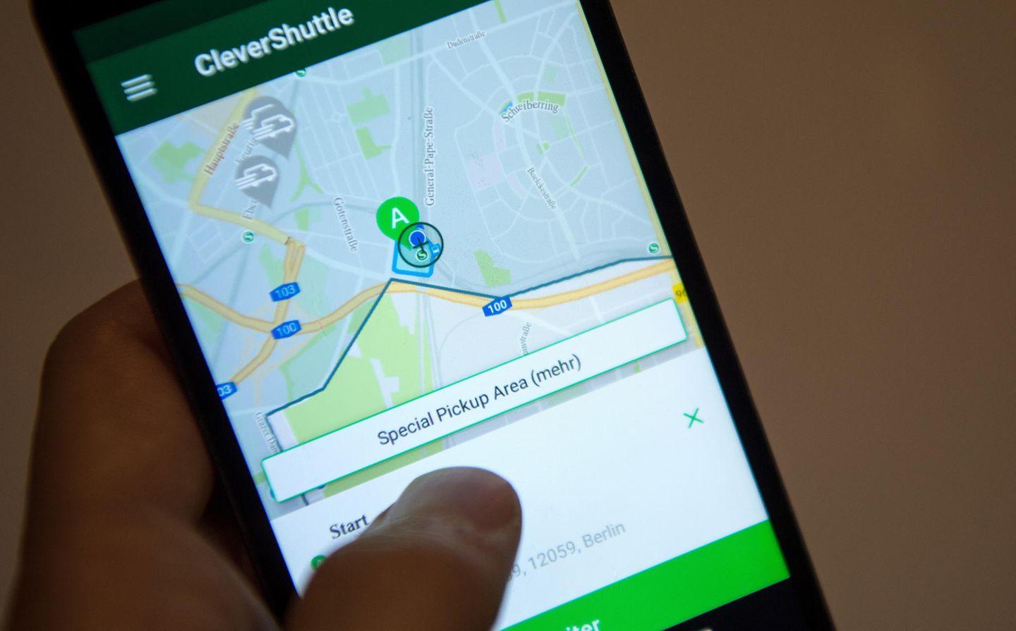 Clever Shuttle: Ein Mann bedient an seinem Smartphone die App des Fahrdienst-Anbieters