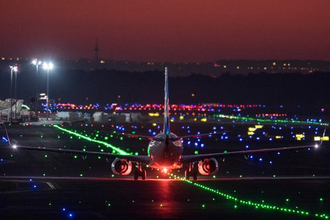Ein Passagierflugzeug rollt im letzten Licht der untergehenden Sonne über die Rollbahn des Flughafens Frankfurt
