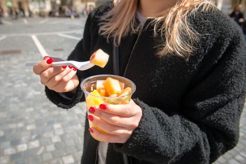 Eine junge Frau isst Obstsalat aus dem Supermarkt