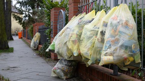 In Berlin hängen gefüllte gelbe Müllsäcke an einem Gartenzaun zur Abholung bereit 