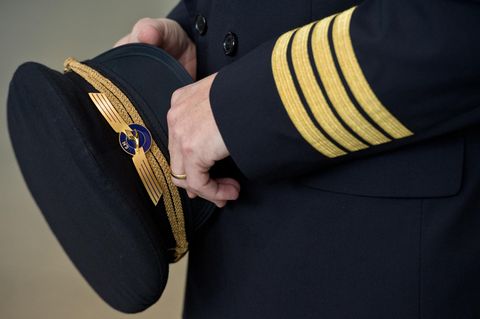 Ein Pilot der Lufthansa hält seine seine Pilotenmütze in der Hand.