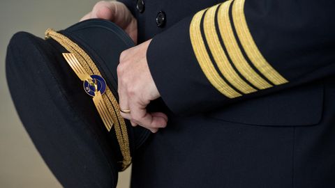 Ein Pilot der Lufthansa hält seine seine Pilotenmütze in der Hand.