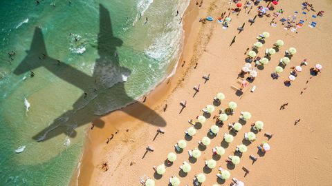 Der Schatten eines Flugzeugs über Meer und Strand