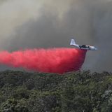 Löschflugzeuge lassen über den vom Feuer betroffenen und bedrohten Gebieten ein pinkfarbenes chemisches Brandschutzmittel ab