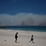 Sorgloser Spaß vor bedrohlicher Kulisse: Während diese Kinder am Strand von Forster, 300 Kilometer nördlich von Sydney, im Sand spielen, wüten im Hintergrund gewaltige Buschfeuer.