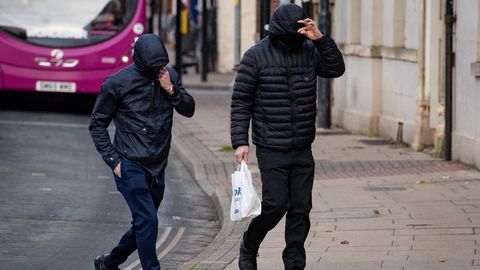 Zwei Männer ziehen ihre Kapuzen ins Gesicht, um nicht erkannt zu werden