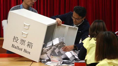 Wahlhelfer leeren eine Wahlurne in einem Wahllokal