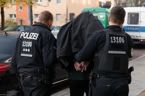 Polizeibeamte führen einen festgenommenen Mann ab