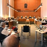 Zu Beginn des Prozesses sitzen elf Angeklagte und Justizbeamte im Landgericht seitlich hinter ihren Anwälten.