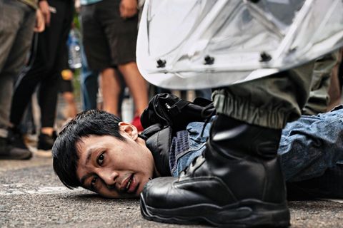 Chinesische Polizisten nehmen einen der Demonstranten fest