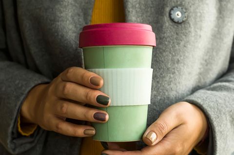 Eine Frau hält einen Becher aus Bambus
