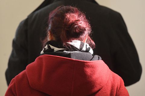 Eine Frau mit rot gefärbten, zum Dutt gesteckten Haaren wendet der Kamera den Rücken zu