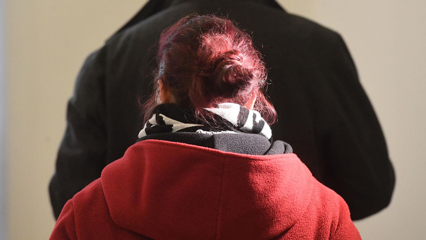 Eine Frau mit rot gefärbten, zum Dutt gesteckten Haaren wendet der Kamera den Rücken zu