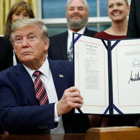 US-Präsident Donald Trump hält eine Mappe mit einem Gesetz hoch, das er gerade im Oval Office unterschrieben hat
