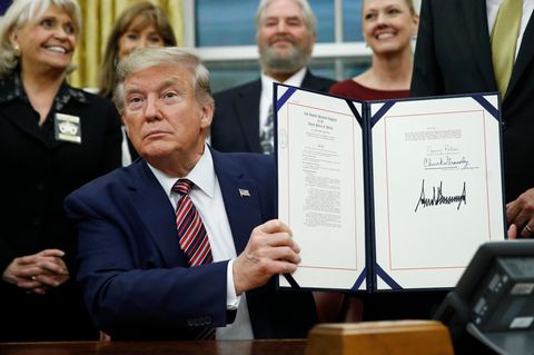 US-Präsident Donald Trump hält eine Mappe mit einem Gesetz hoch, das er gerade im Oval Office unterschrieben hat
