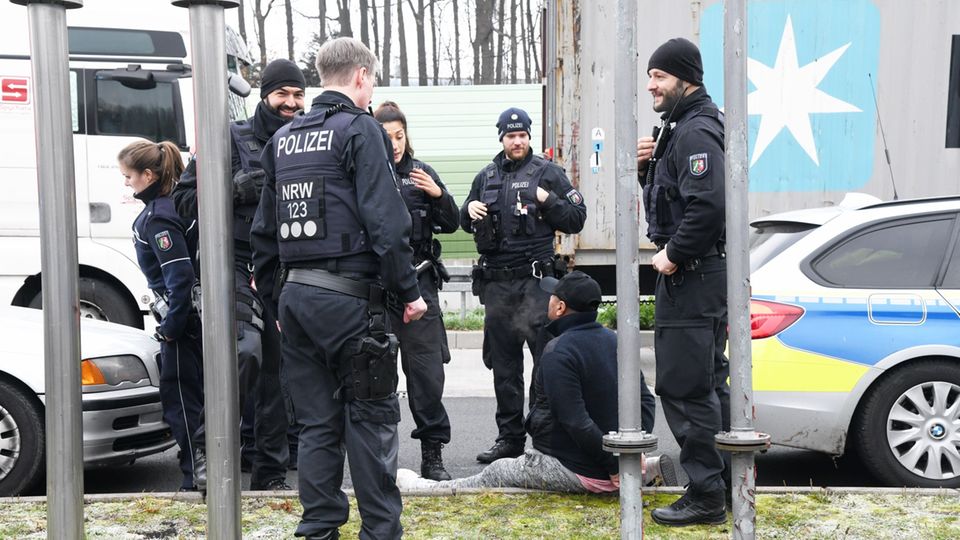 Festnahmen nach Massenschlägerei mit einem Schwerverletzten Polizisten umringen einen Festgenommenen, der auf dem Boden sitzt
