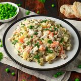 Oliviersalat - oder auch Russischer Salat  Der französische Koch Lucien Oliver eröffnete Mitte des 19. Jahrhunderts ein Restaurant namens "Ermitage" in Moskau. Es war ein Salat, der ihm zu Weltruhm verhelfen würde. Der Oliviersalat - oder auch Russischer Salat genannt - wurde ursprünglich mit Huhn, Kalbszunge, schwarzem Kaviar, Blattsalat, gekochtem Flusskrebs, kleinen Cornichons, Kapern und hartgekochten Eiern zubereitet. Heute gibt es den Russischen Salat in einer simpleren Version: mit Kartoffeln, Möhrchen und Erbsen aus dem Glas, Eier, Essiggurken - und viel Majonnaise.