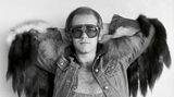 Elton John in Latzhose und Jeansjacke mit Fell