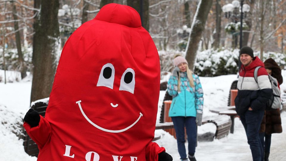 Schnee und Sex In einem roten Plüschkostüm geht jemand als Kondom verkleidet durch einen verschneiten Park