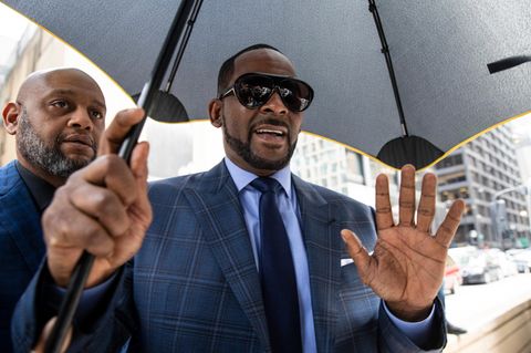 Sänger R. Kelly mit einem Regenschirm und Body Guard an seiner Seite