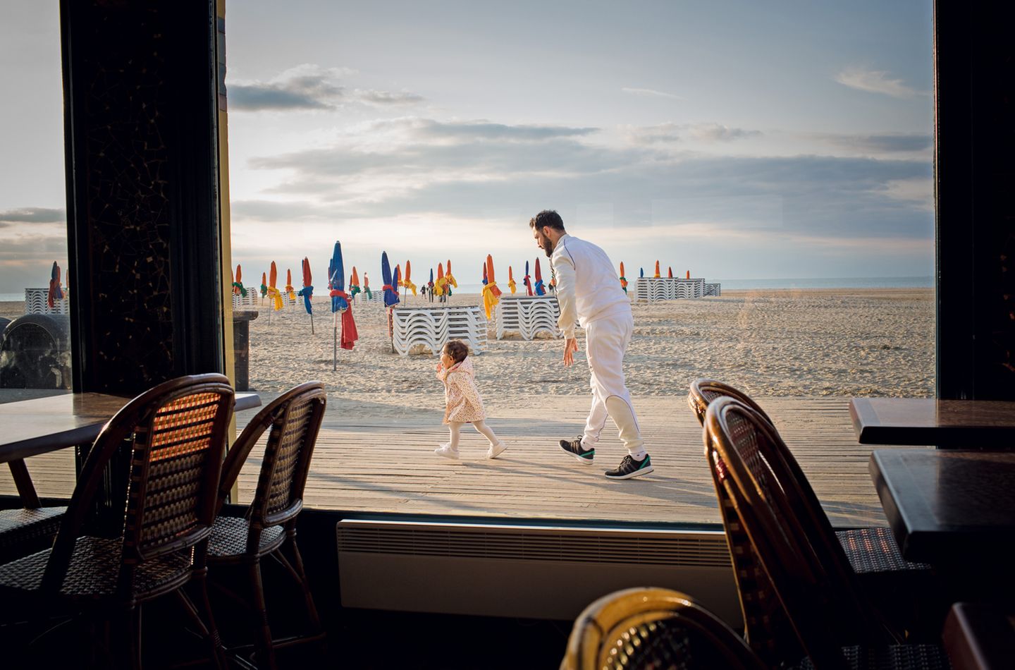 Ein Vater beim Spiel mit seiner Tochter vor einer Strandbar in Deauville. 
