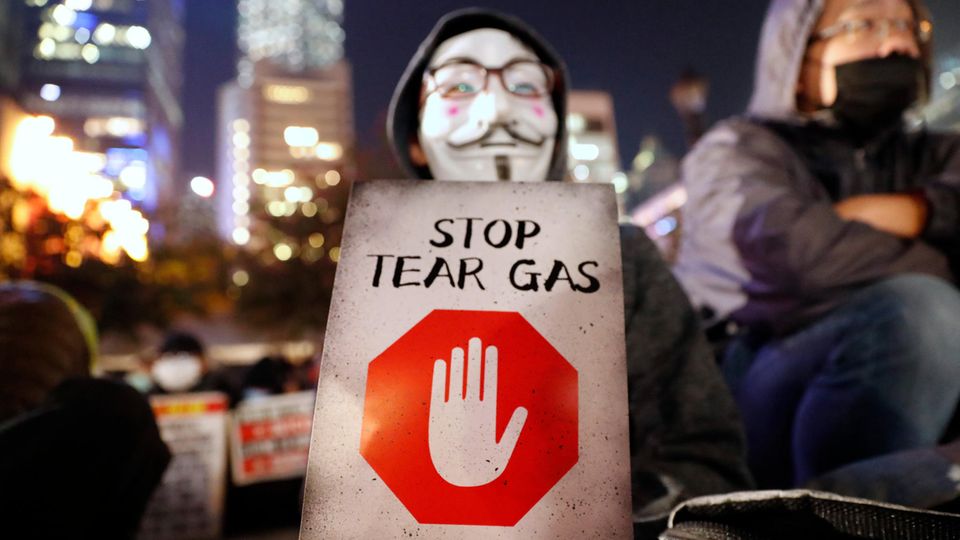 Ein maskierter Demonstrant hält ein Schild mit der Aufschrift "Stoppt Tränengas" während einer Kundgebung gegen den Einsatz von Tränengas durch die Polizei