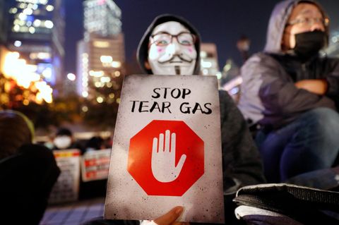 Ein maskierter Demonstrant hält ein Schild mit der Aufschrift "Stoppt Tränengas" während einer Kundgebung gegen den Einsatz von Tränengas durch die Polizei