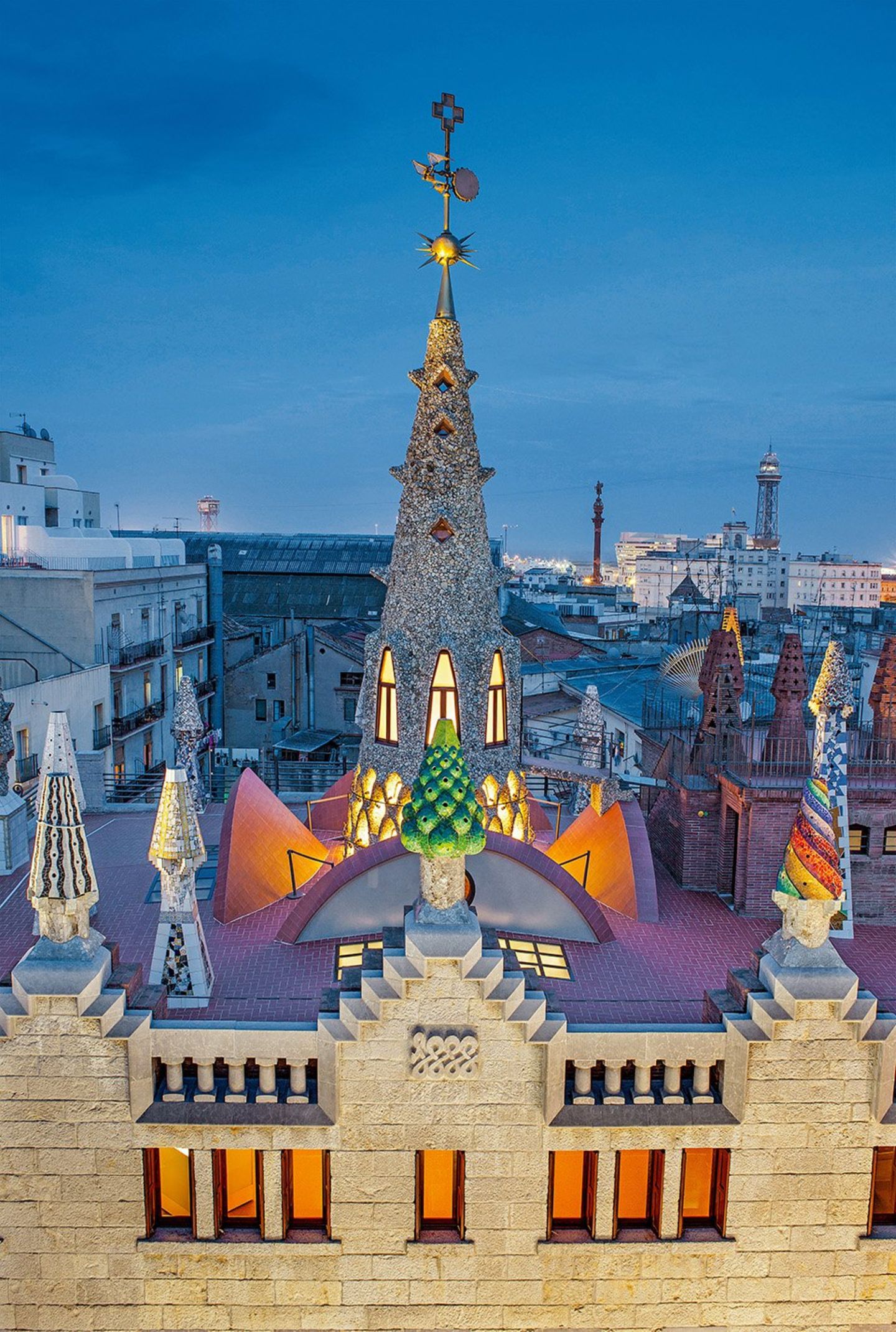 Gaudí Palacio Güell, 1885_1889, Calle Nou de la Rambla, Barcelona. Wo man sich auch hinstellt in der Calle de la Rambla, es wird schwerfallen, den Palast, den Gaudí für seinen Freund Eusebi Güell erbaute, ganz in den Blick zu bekommen. Das liegt gewiss nicht an seiner Größe: Der Bauplatz ist nur 18 mal 22 Meter groß. Doch die Straße ist so eng, dass man nicht weit genug zurückweichen kann. Die farbenfrohe Gestaltung der Dachaufsätze mit ihren Trencadís (Mosaike aus unterschiedlich großen Bruchstücken keramischer Fliesen, Marmor oder Glasscherben) macht das flache Dach zu einem stilisierten Wald inmitten der Enge der Altstadt. Um die zentrale Kuppel gruppieren sich Schornsteine und auch Belüftungen für die Ställe im Untergeschoss.