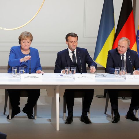 Selensky, Merkel, Macron und Putin sitzen in einer Reihe an Mikrofonen