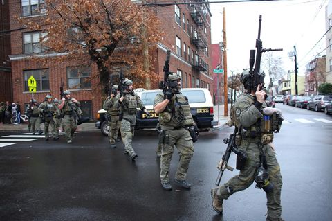 Polizisten gehen schwer bewaffnet über eine Straße