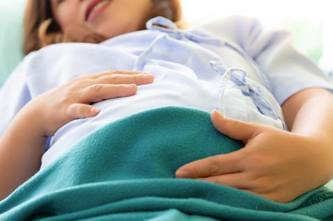 Eine schwangere Frau hält sich den Bauch
