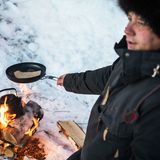 Der Rentierhirte Carl-Johan Utsi macht eine Pause und wärmt Elchfleisch und Brot über offenem Feuer auf, um sich für den langen, kalten Arbeitstag zu stärken