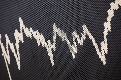 Auf schwarzem Hintergrund ist eine weiße Dax-Kurve zu sehen, die sich über den Hintergrund mäandert