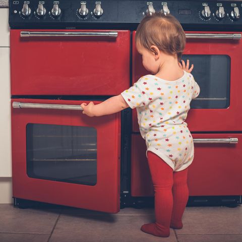 Ein Kleinkind steht am Backofen