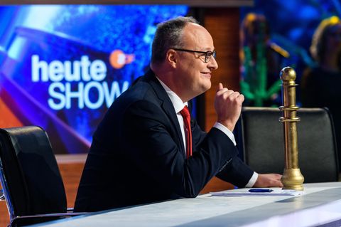 Oliver Welke sitzt am Moderationspult, neben ihm steht der "goldene Vollpfosten"
