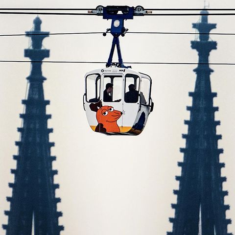 28.03.2019, Nordrhein-Westfalen, Köln: Eine Seilbahngondel der Kölner Seilbahn fährt über den Rhein, im Hintergrund sind die Spitzen des Kölner Doms zu sehen. Nach mehr als anderthalb Jahren Zwangspause fährt die Kölner Seilbahn wieder. Die Seilbahn war...