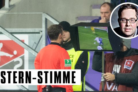 Ein Schiedsrichter steht am Spielfeldrand und schaut sich eine Szene auf einem Monitor an