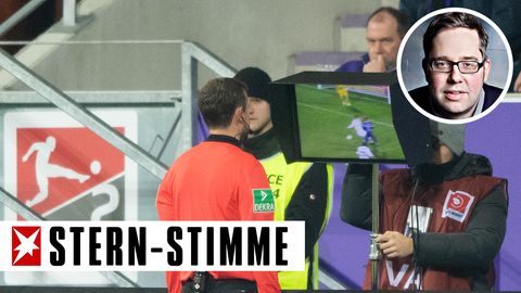 Ein Schiedsrichter steht am Spielfeldrand und schaut sich eine Szene auf einem Monitor an